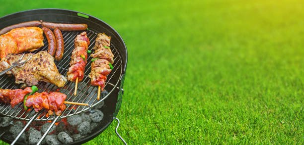 Delicious grilled meat with vegetables sizzling over the coals on barbecue