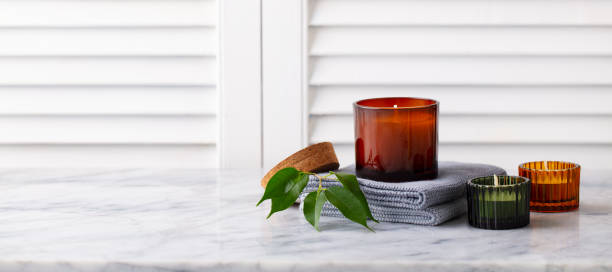 Scented candles in glass holders on marble table White background Copy space