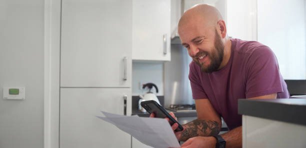 A man stood in his kitchen reading through a letter regarding his finances