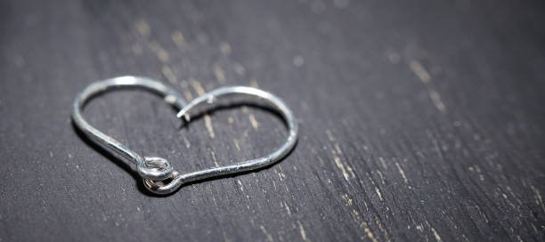 Horizontal shot of heart-shaped fish hooks on a dark background