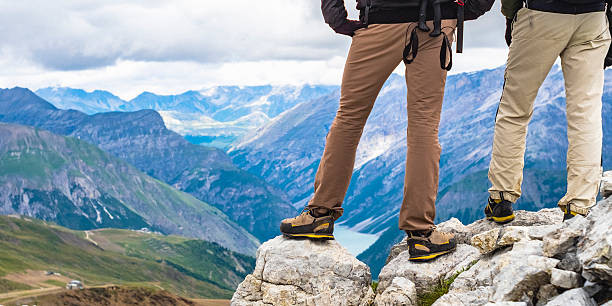 Hiker on the top of the mountain peak close up on hiking boots