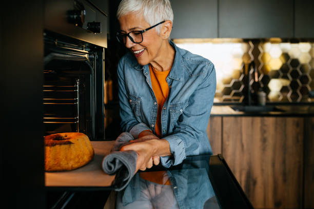 Senior woman baking bundt cake in her kitchen and waiting for it to be done