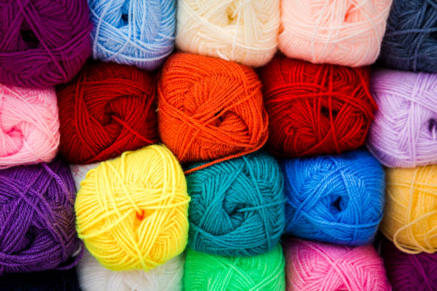 Close up image depicting multi colored balls of wool for sale at the art and craft store. The balls of wool are displayed stacked on top of each other and in a row. Room for copy space.