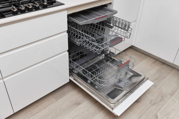 Modern built-in empty dishwasher with open door in the kitchen .