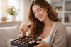 Woman choosing a chocolate from an open box of assorted chocolates at home