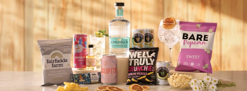 Craft Gin Club subscription box featuring Lincoln Springtide Gin, tonic mixers, kombucha, cocktail ingredients, gourmet snacks and popcorn arranged with a gin and tonic serve.